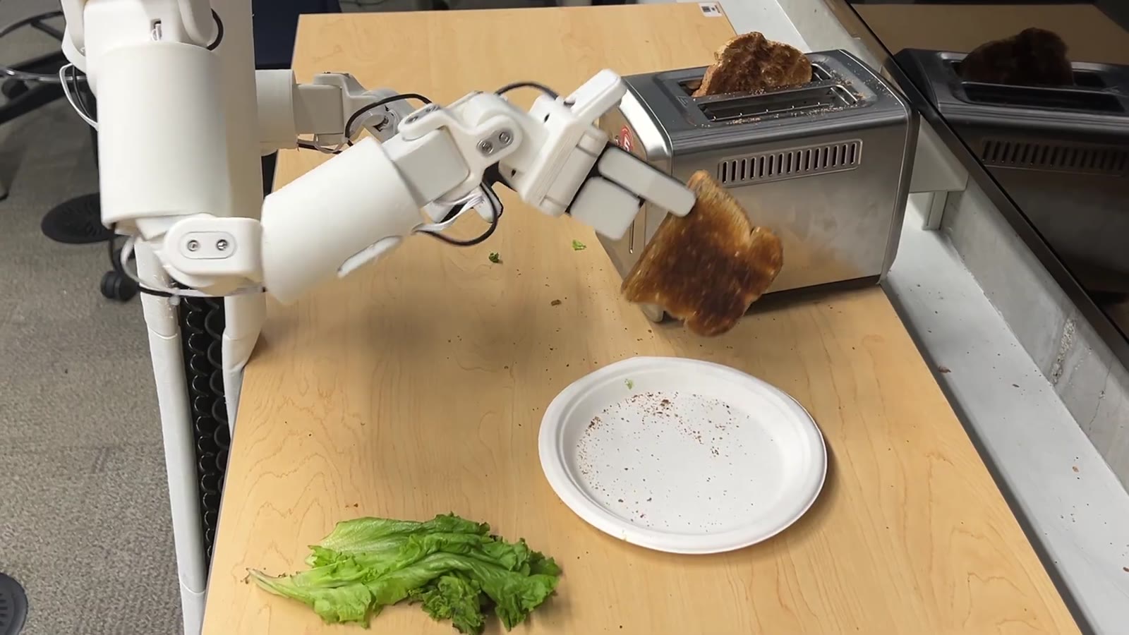 The robot lifting a toasted slice clear of the toaster
