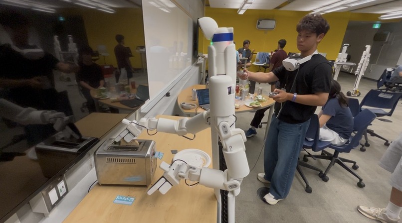 Operator wearing a Meta Quest headset, teleoperating the Bracket Bot's arms toward the toaster