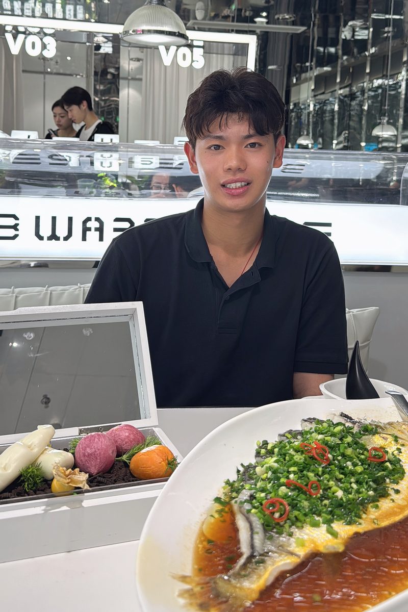 Max Yuan in a black polo at a restaurant table